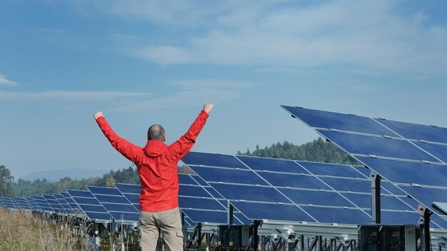 Male engineer at work place, solar panels plant industy in background