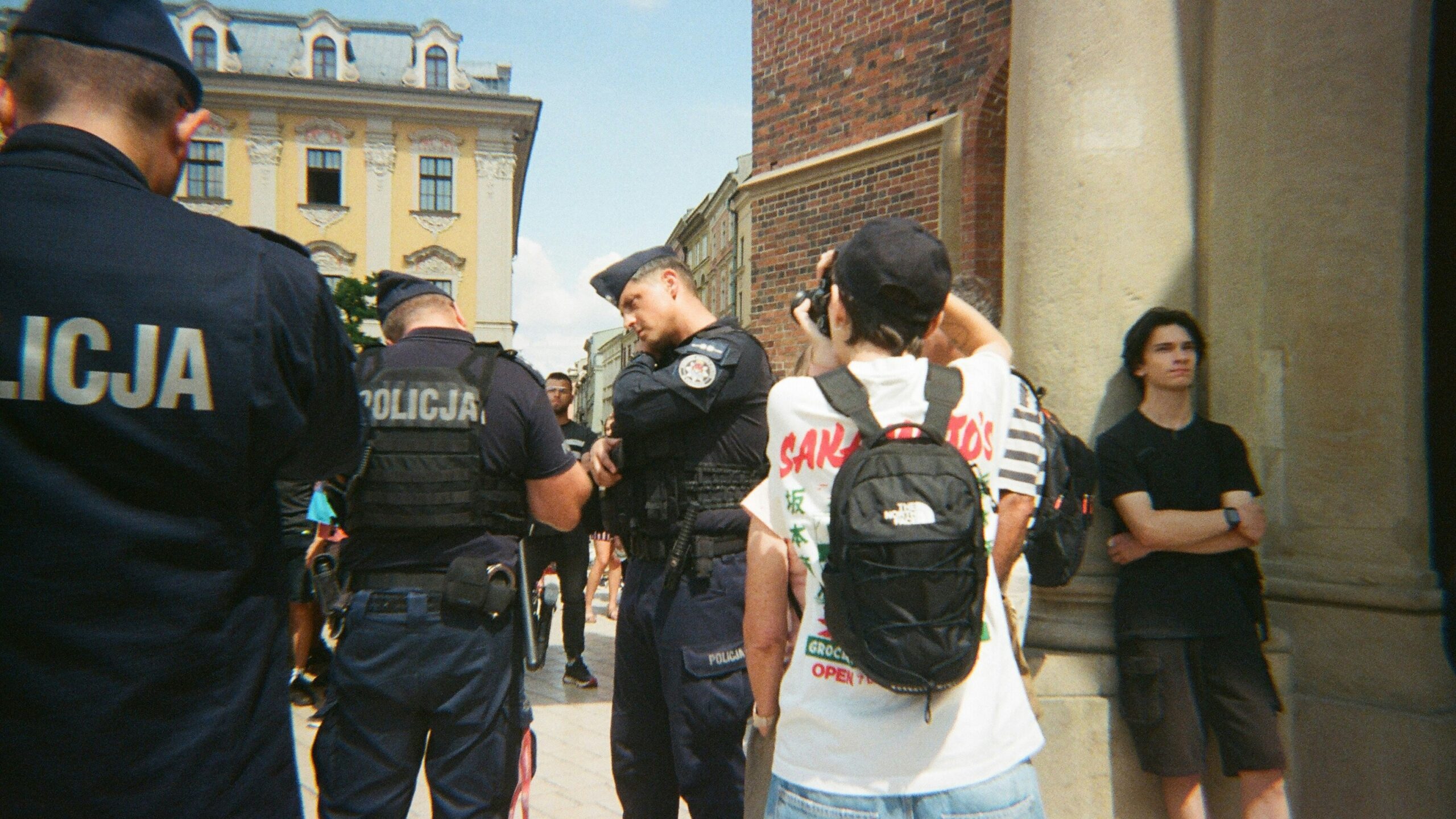 Police officers stand near civilians on a street.