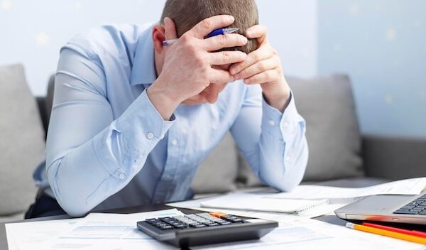 Distressed man sit at desk paying bills feel stressed having financial problems