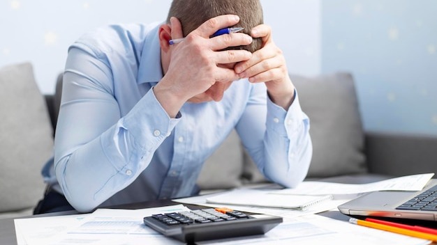 Distressed man sit at desk paying bills feel stressed having financial problems