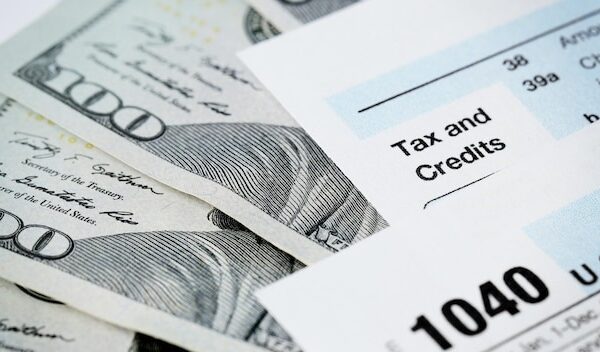 1040 Individual Income Tax Return Form with one hundred dollar bills on white background close up