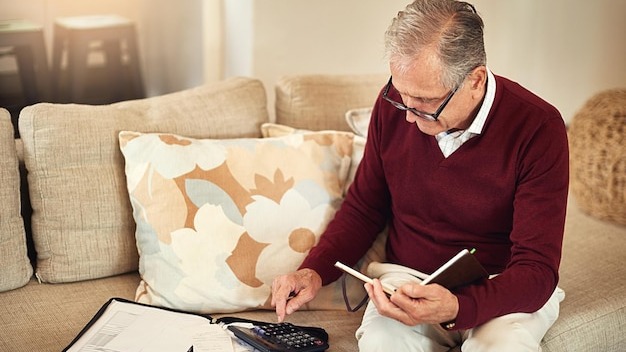 Senior man notebook and calculator on sofa for budget planning and savings account for retirement Elderly person bills and couch in lounge for mortgage personal debt and loan repayment ay home