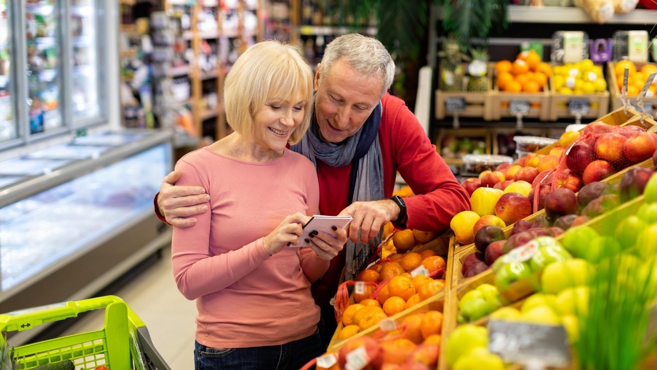 Smiling customers senior couple walking in supermarket