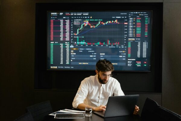 Businessman using laptop in office analyzing stock market charts. Professional finance and investment concept.