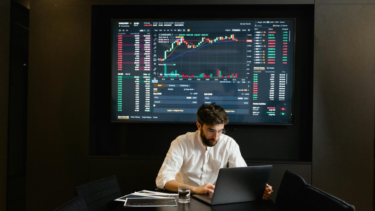 Businessman using laptop in office analyzing stock market charts. Professional finance and investment concept.