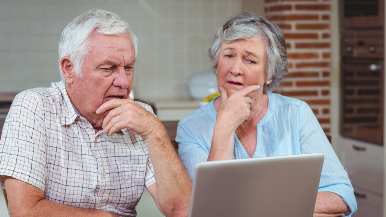 Thoughtful senior couple using laptop