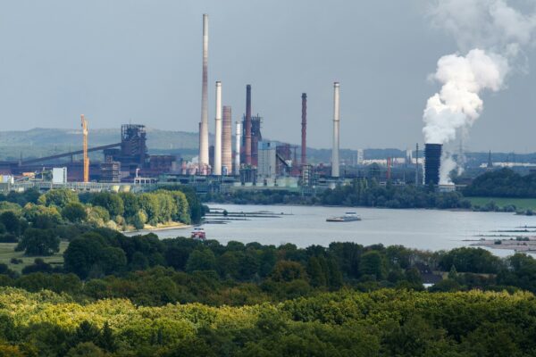 Industrial complex with smokestacks near a body of water.