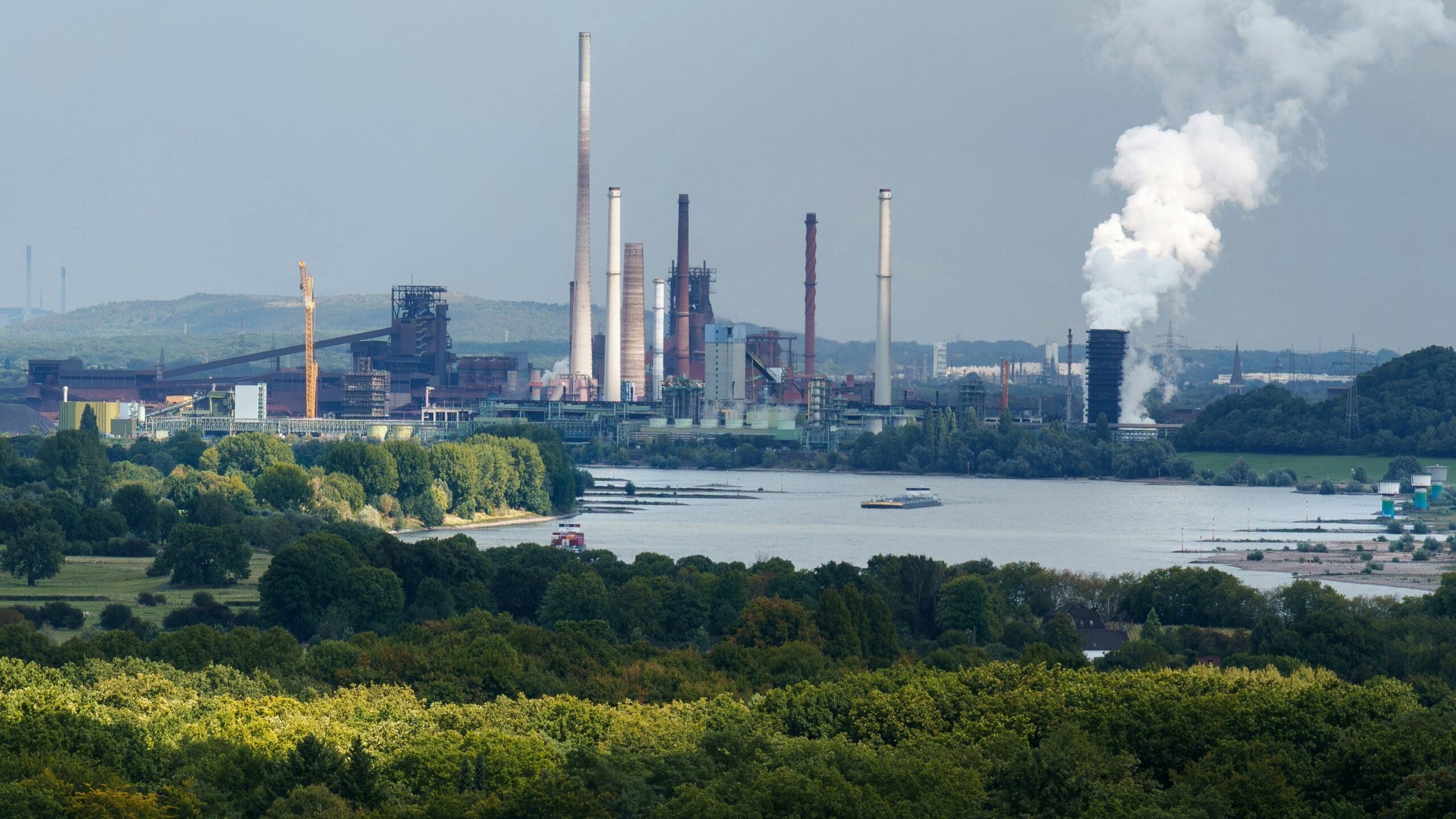 Industrial complex with smokestacks near a body of water.