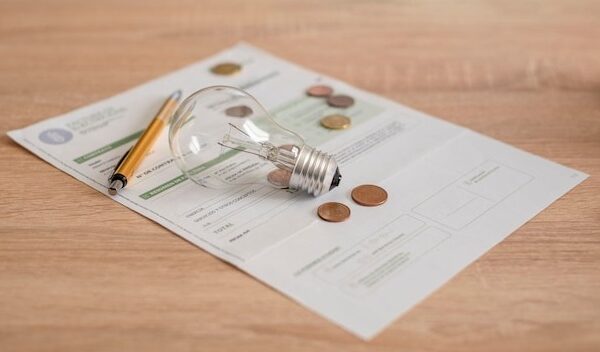 Electricity bill with light bulb several coins and pen on the desk Concept of electricity prices and tax payments