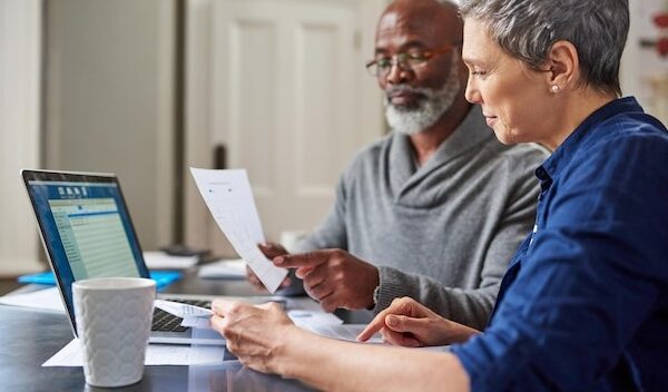 Laptop documents and finance with a senior couple busy on a budget review in the home together Accounting taxes or investment planning with a mature man and woman looking at insurance or savings