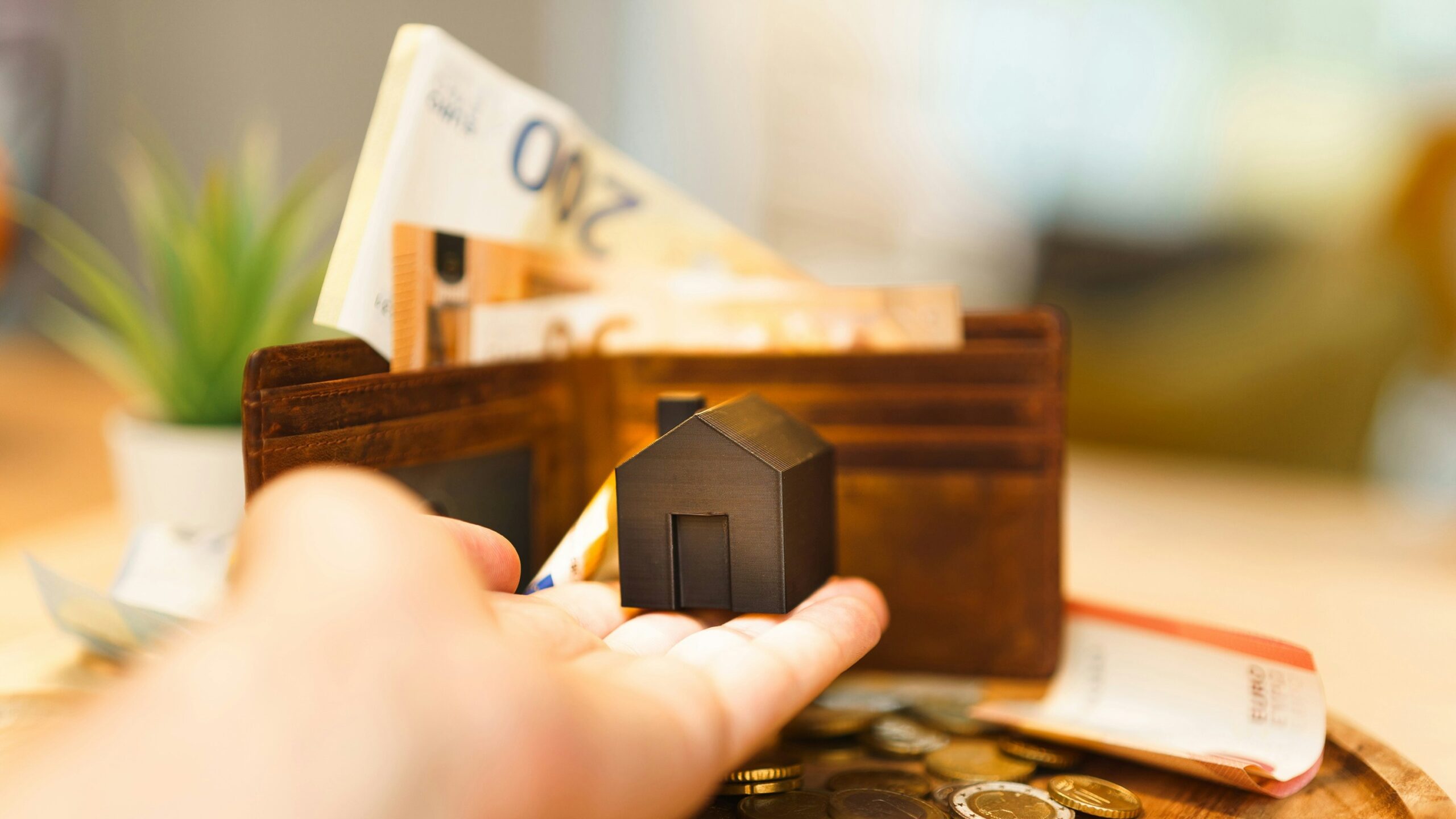 A person holding a small house and some money