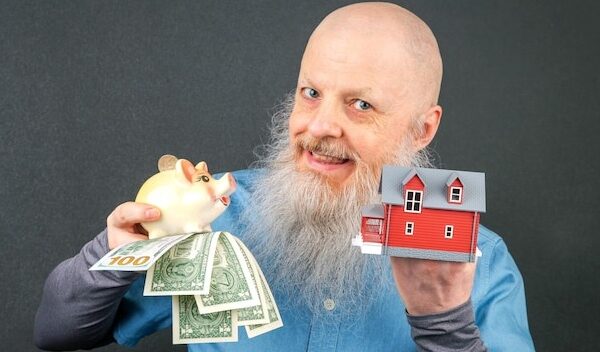man displaying a piggy bank overflowing with money and a miniature house emphasizing themes