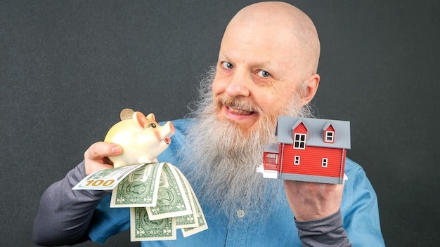 man displaying a piggy bank overflowing with money and a miniature house emphasizing themes