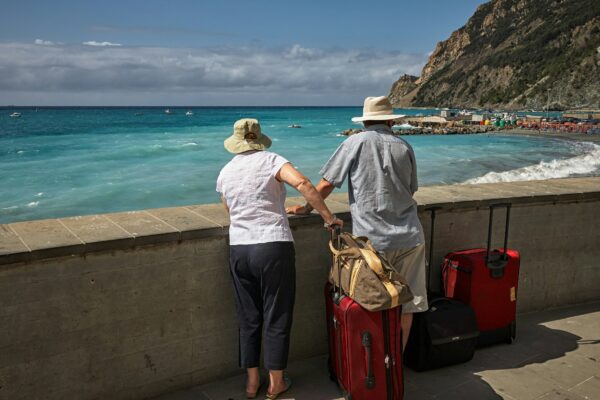 man and woman standing beside concrete seawall looking at beach