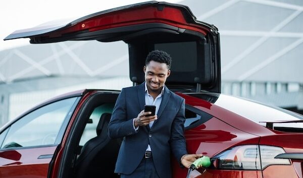 Man in suit using cell phone while waiting for car to charge