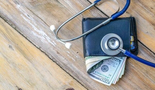 Close-up of paper currencies in wallet with stethoscope on table