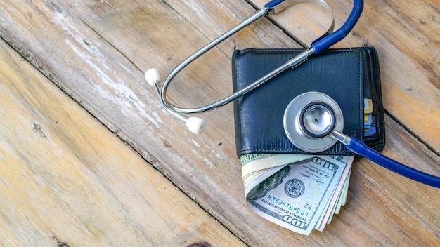 Close-up of paper currencies in wallet with stethoscope on table