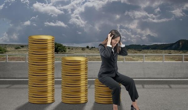Asian businesswoman sitting on decreasing coin graph