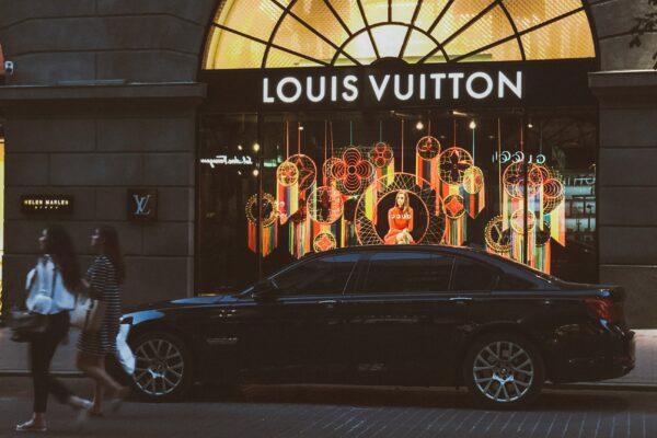 black sedan parking near Louis Vuitton building and two women walking near road
