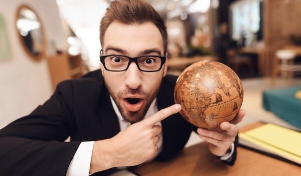 A man in a business suit is holding a globe in his hands.