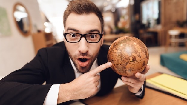 A man in a business suit is holding a globe in his hands.