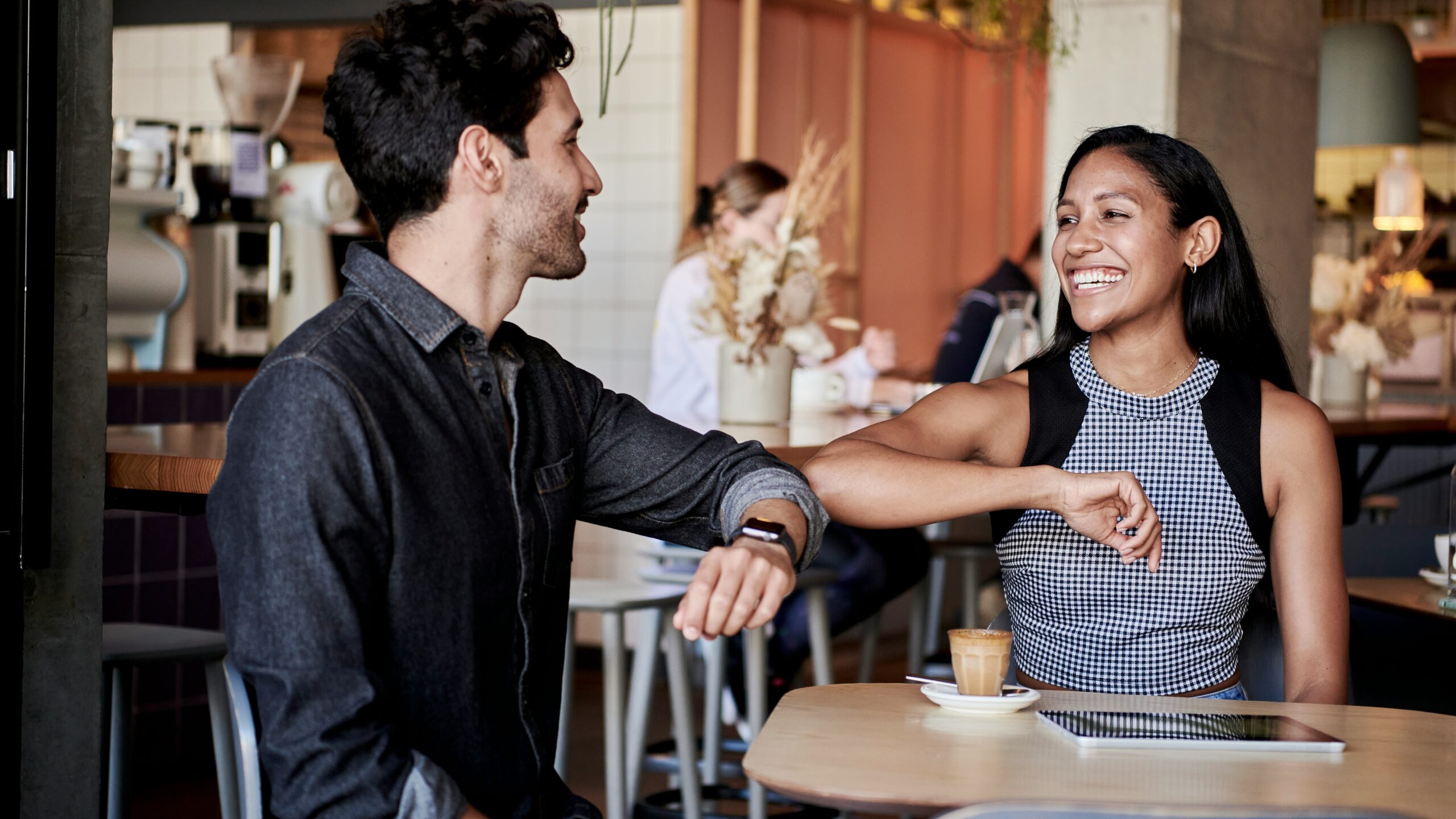 man in black shirt elbow bumping with woman in a restaurant