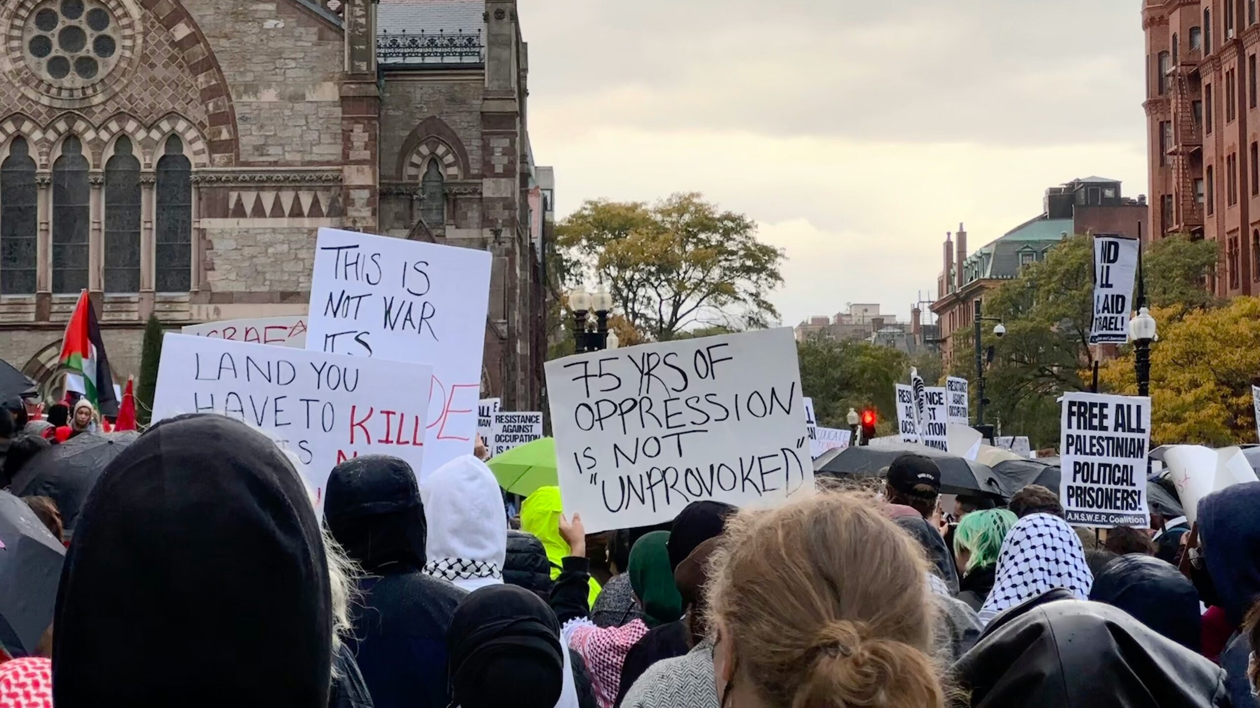 a crowd of people holding signs in front of a church