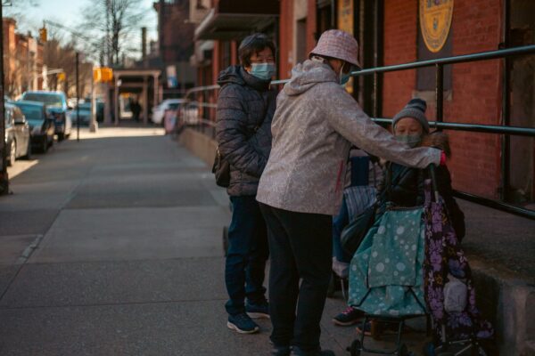 a group of people standing on a sidewalk next to a building