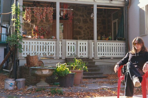 Woman sitting in red chair outside rustic house