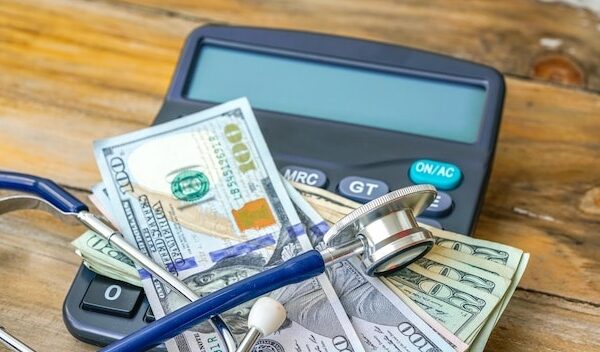 Close-up of calculator with stethoscope and paper currencies on table