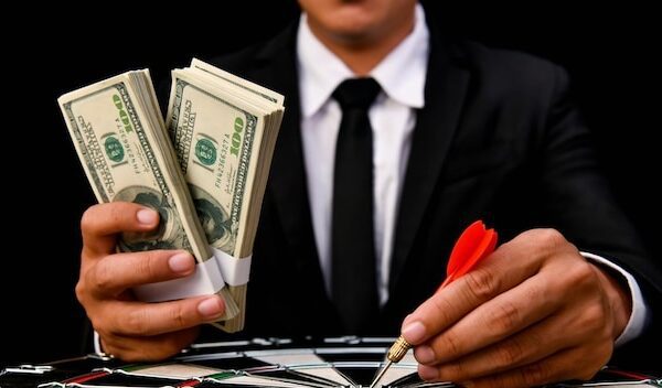 Cropped image of businessman holding currency over dartboard