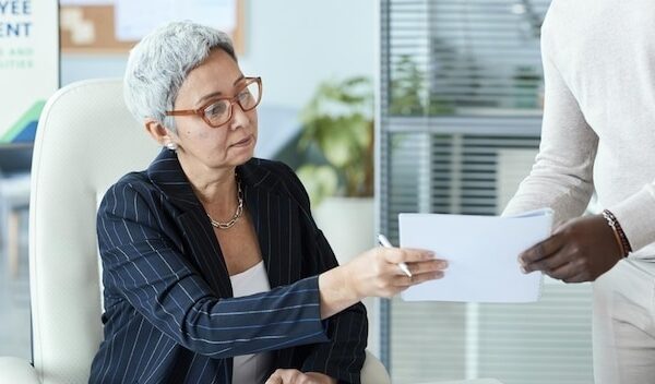 Senior businesswoman signing documents in business meeting at office