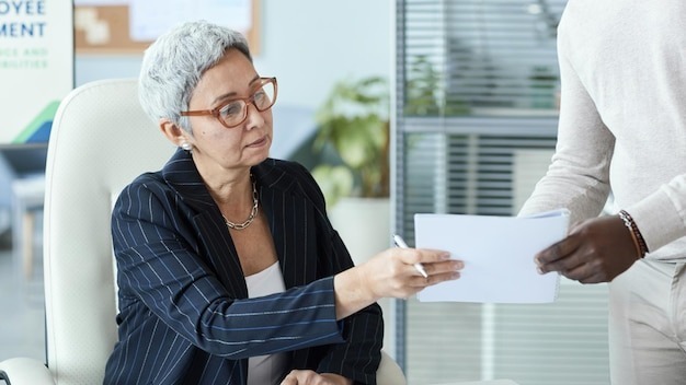Senior businesswoman signing documents in business meeting at office