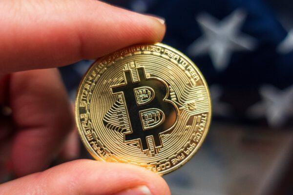 a hand holding a bit coin in front of an american flag