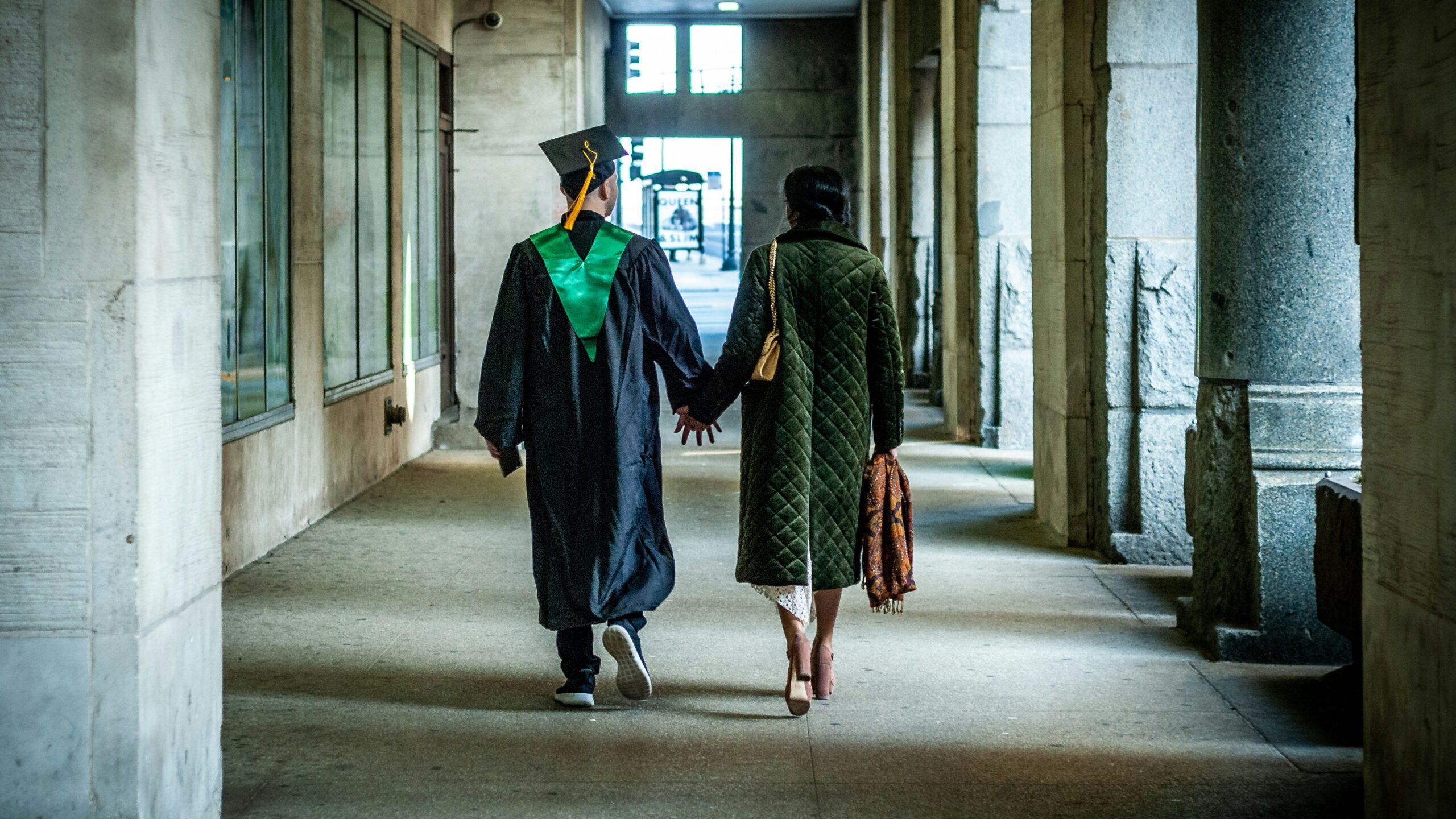 two people walking down a hallway holding hands