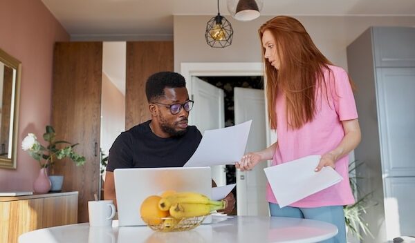 Serious african man read papers and caucasian woman discuss unpaid internal bills
