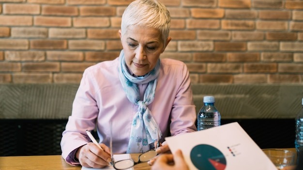 Beautiful senior businesswoman signing a contract for work after conducting a job interview.