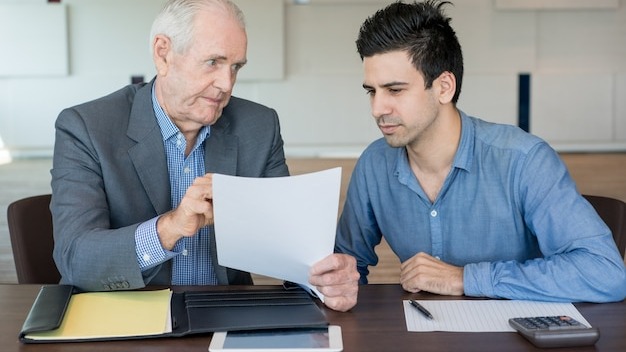 Serious boss explaining document to colleague