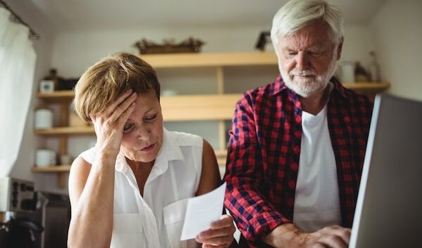 Senior couple paying bills online on laptop