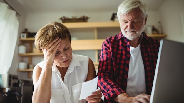 Senior couple paying bills online on laptop