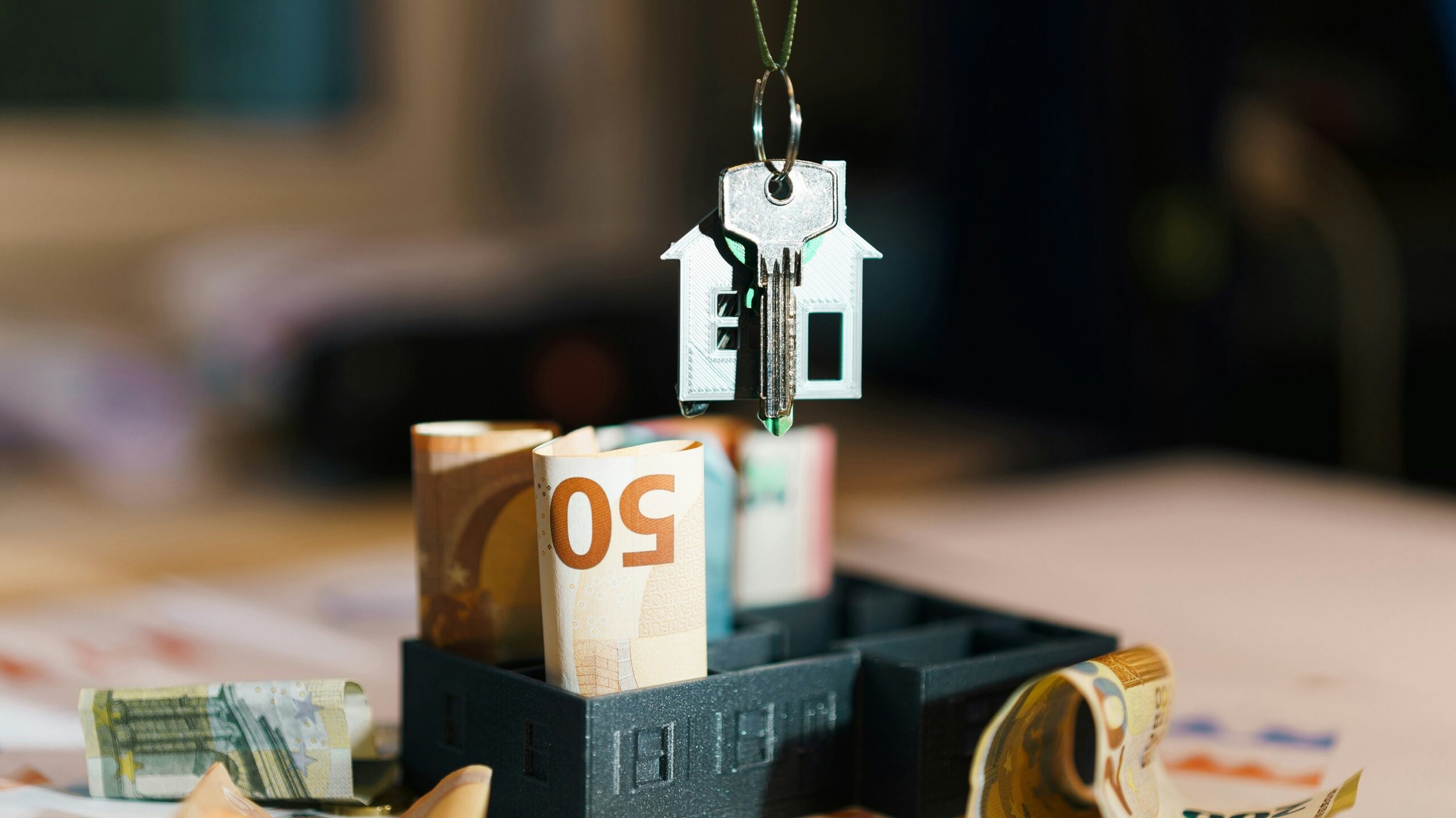 A house hanging from a string on top of a pile of money