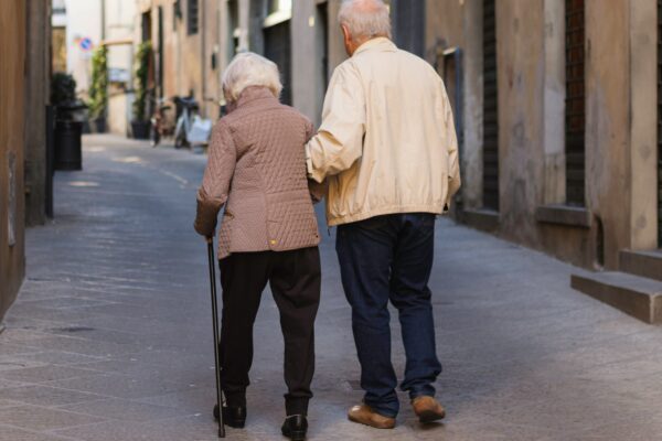 an older couple walking down a narrow street