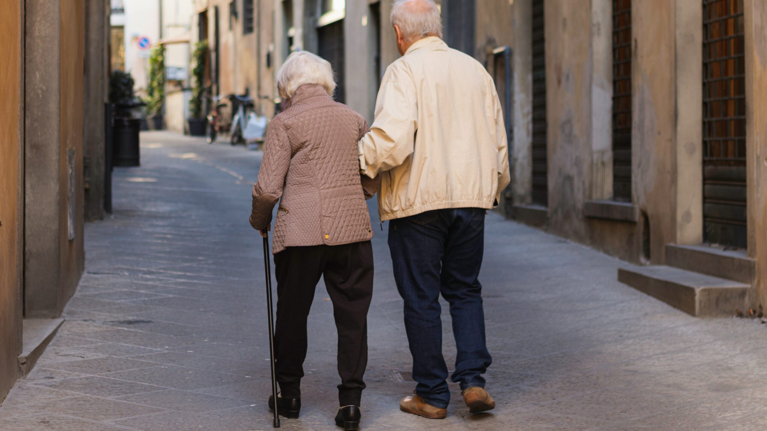 an older couple walking down a narrow street