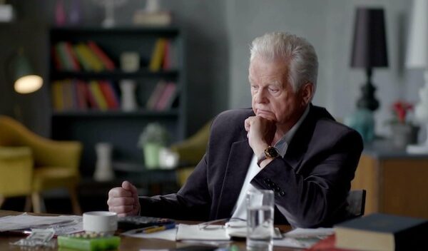 Concentrated senior man working with documents at desk in living room