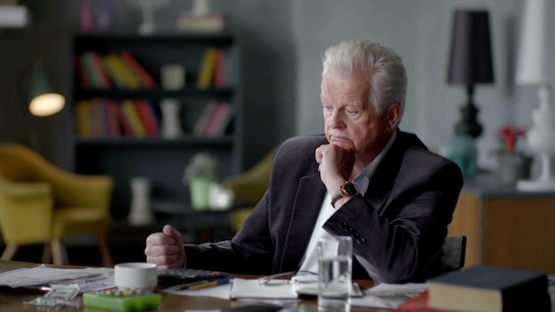 Concentrated senior man working with documents at desk in living room