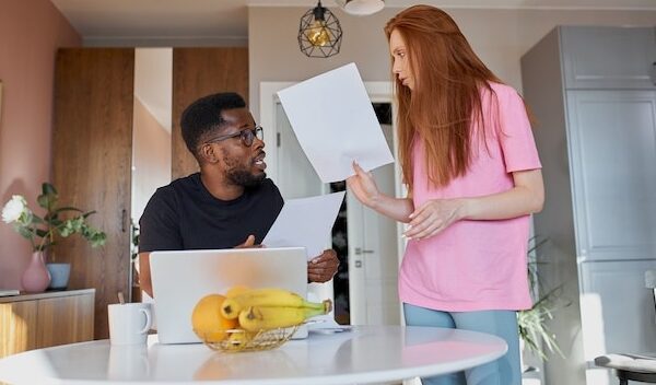 Interracial couple reading mail and checking accounting in the kitchen at home