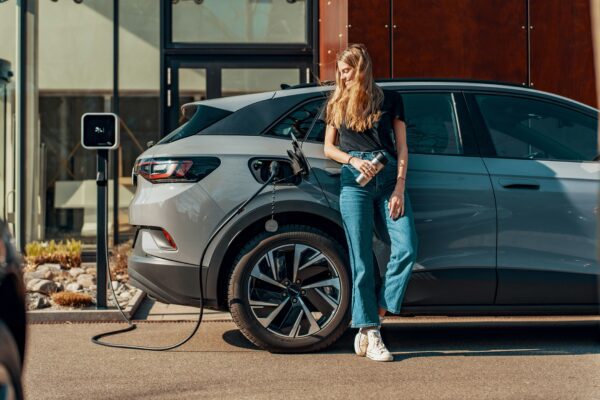 a woman standing next to a blue car