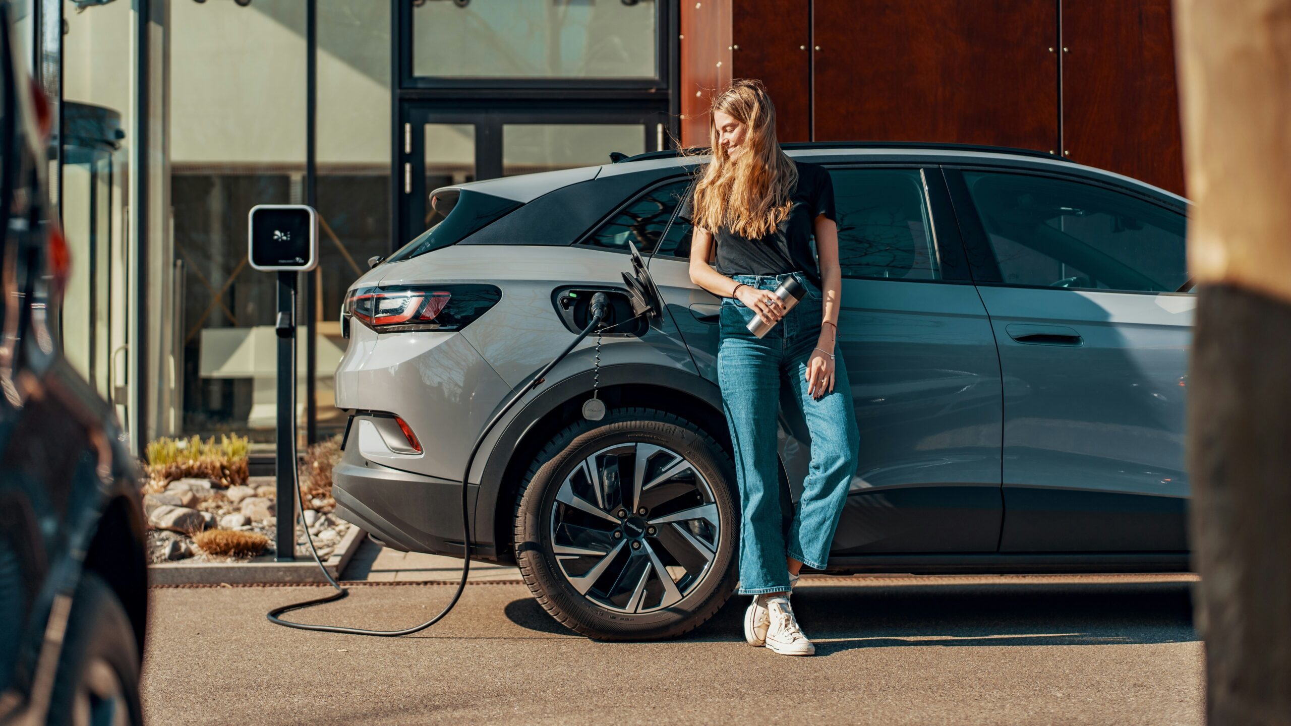 a woman standing next to a blue car