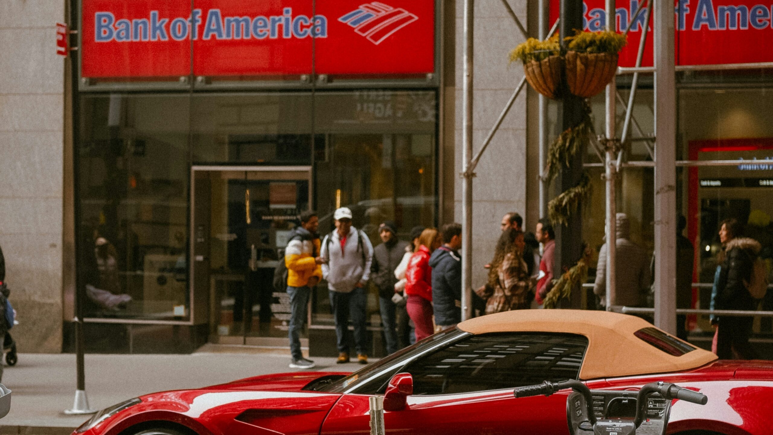 a red sports car is parked in front of a bank of america