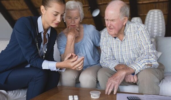 Female doctor and senior couple discussing over medicine